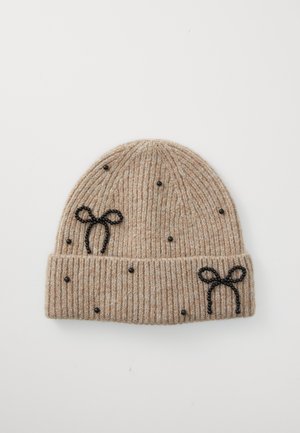 Gehaakt beanie in beige met geribbelde structuur, versierd met zwarte kralenaccenten en twee zwarte strikontwerpen aan de voorkant.