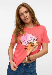 Koralowa bawełniana koszulka z graficznym nadrukiem abstrakcyjnych twarzy w pastelowych kolorach, okrągły dekolt i krótkie rękawy.