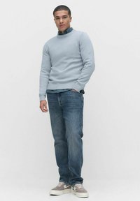 Vaaleansininen neule, jossa on ribattu kaulus, yhdistettynä sinisiin farkkuihin. Harmaa-valkoiset lenkkarit viimeistelevät asukokonaisuuden. Yhtenäinen sileä pinta.