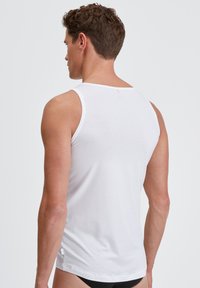 Witte katoenen tanktop met een ronde hals, zonder mouwen, en een relaxte pasvorm. Gladde textuur met subtiele stiksels aan de zoom.