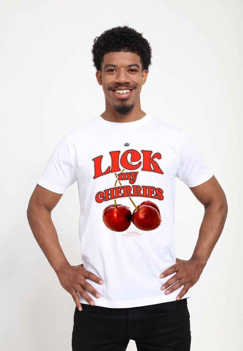 Hvid bomulds T-shirt med fed tekst "SLIK mine KIRSEBAER" i rød, med to røde kirsebærgrafik, sat mod en ensfarvet baggrund.