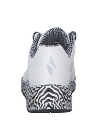 Sneaker blanche avec une semelle extérieure noire et blanche à motifs, un supérieur texturé et un détail de logo au niveau du talon. Présente un col rembourré et une doublure respirante.