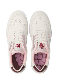 Witte sneakers met lichtroze accenten, perforated teenbox en zachte voering. Kenmerkend zijn het druif-thema in de binnenzool en het logo op de tong.