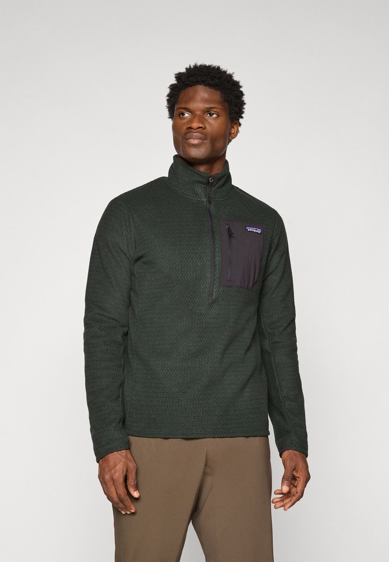 Pull-over en polaire vert avec col haut, zip quart, corps texturé et poche poitrine noire. Présente le logo Patagonia.