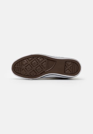 Podeszwa buta z brązowym gumowym bieżnikiem z wzorami w diamenty i linie, z widocznym logo Converse All Star na środku.