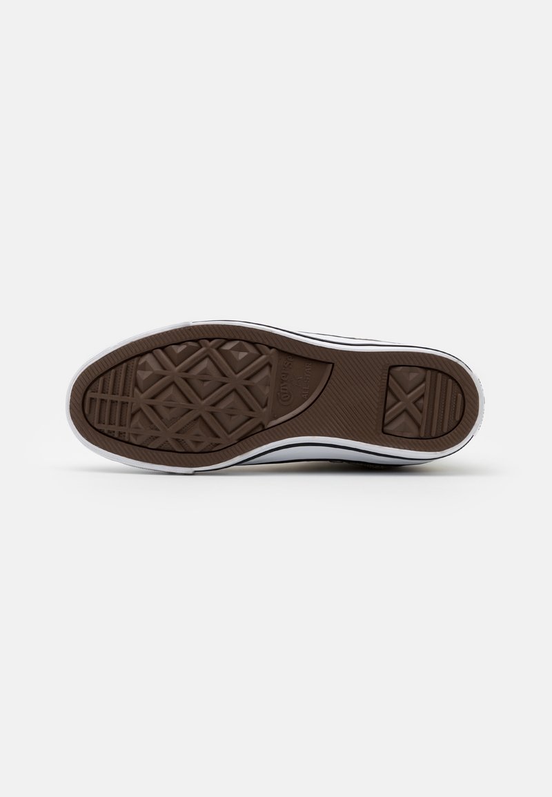 Sole boty s hnědou gumovou podrážkou zdobenou diamantovými a liniovými vzory, s viditelným logem Converse All Star uprostřed.