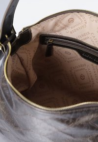 Borsa a mano in pelle marrone aperta per mostrare l'interno in tessuto beige con il logo ripetuto "CAFÉNOIR" e una tasca con zip.