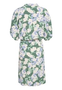 Blommig klänning med grön bakgrund som har stora vita och blå blommor, krage och midjebälte. Lös, mjuk tyg.