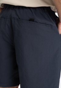 Navy shorts i lättviktsmaterial, med elastiskt midjeband, bakficka och sydda detaljer. Slät textur med en subtil lyster.