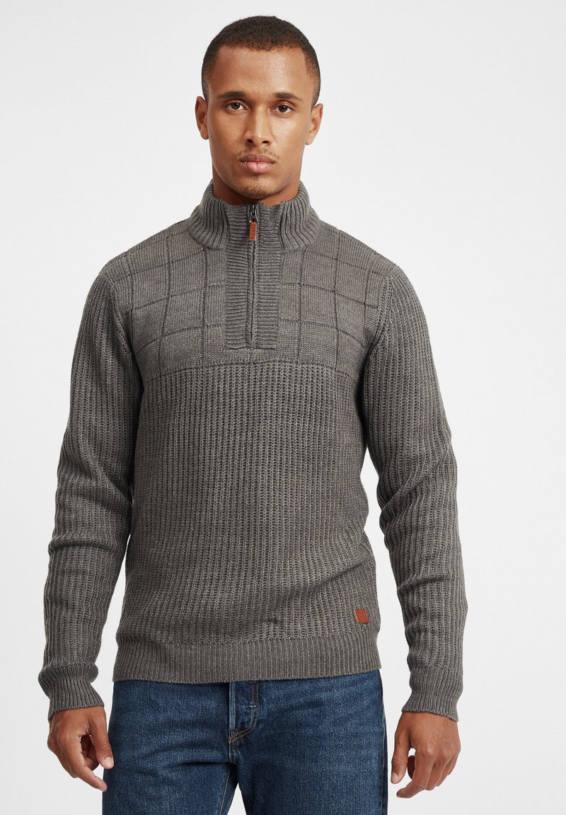 Grauer Strickpullover mit einem Viertel-Reißverschlusskragen, der ein strukturiertes Muster und gerippte Bündchen aufweist. Lederlogo-Patch am Saum.