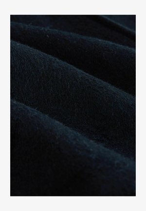 Sule lähedalt tume sinine villane kangas, millel on pehme, karvane tekstuur ja nähtavad voldid, mis loob varjutatud servad.