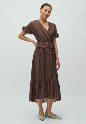 Hnedé šaty po kolená s zavinovacím dizajnom, krátkymi volánovými rukávmi, pásom v páse a vrstveným lemom. Nosené s farebnými balerínami.