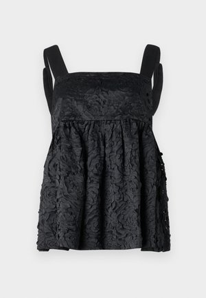 Musta peplum-toppi, jossa on kukkatekstuuri, neliömäinen kaula-aukko ja leveät hihat, yhdistettynä mustiin leveälahkeisiin housuihin ja metallinhohtoiseen käsilaukkuun.
