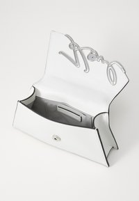 White leather handbag with a silver metal closure and embossed logo. Interior is lined, featuring a pouch and contrasting black trim.