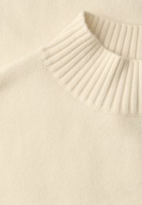Kremowy sweter z prążkowanym, wysokim kołnierzem i gładką fakturą, wykonany z miękkiej dzianiny o prostym wzornictwie.