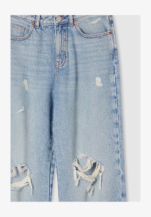 Jeans in denim azzurro chiaro, con strappi grandi sulle ginocchia, bordi sfrangiati e dettagli di cuciture arancioni su tasche e vita.