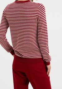 Punavalkoraidallinen villapaita, jossa vuorottelevat valkoiset ja metallinhohtoiset langat. Pyöreä päänti ja resorireunukset hihoissa ja helmassa. Sileä pinta.