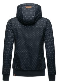 Dunkelblaue Jacke mit einer Kapuze im Chevron-Muster und gepunkteter Textur am Körper. Abgeschlossen mit gerippten Bündchen und einem Logo-Patch.