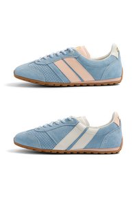 Baskets en daim bleu avec perforations, semelles en caoutchouc et deux bandes latérales roses ou blanches, vues de profil gauche et droit sur fond blanc.