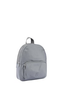 Mochila de nylon gris con forma redondeada, compartimento principal con cremallera y bolsillo frontal. Cuenta con un asa en la parte superior y un detalle de logotipo en relieve.