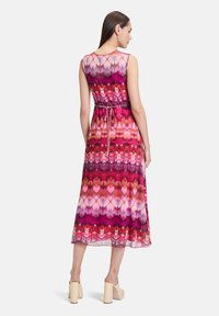 Maxikleid mit einem mehrfarbigen Muster in Pink-, Rot- und Lilatönen; ärmelloses Design mit gebundenem Taillenbereich und fließendem Stoff.