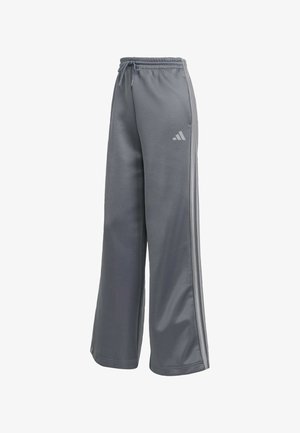 Sivé teplákové nohavice z mäkkého materiálu, so šnúrkou v páse, širokými nohavicami a tromi vertikálnymi pruhmi po stranách s logom.