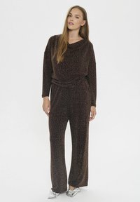 Bruine velours jumpsuit met een kraag, lange mouwen en sprankelende accenten overal; losvallend, met een brede pijpdesign.