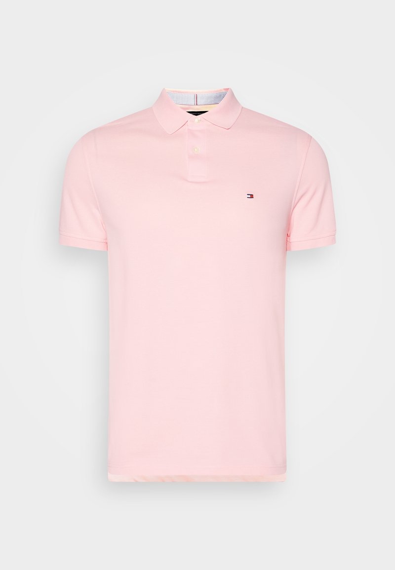 Polo rose en tissu doux, avec un col classique, des manches courtes et un petit logo sur la poitrine. Design et structure simples.