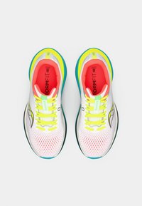 Zapatillas deportivas blancas con parte superior de malla, con cordones amarillos, acentos neón y un interior rosa. Logo distintivo en el lateral.