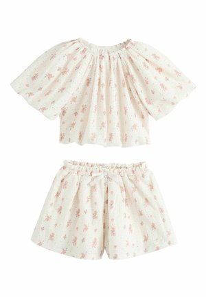 Hvidt todelt børnetøj med pink blomstermønster, der består af en indsamlet off-shoulder top og shorts med elastisk talje og dekorativ sløjfe.