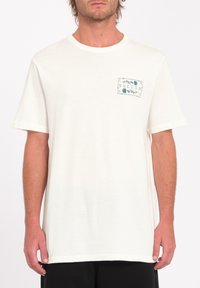 Cream short-sleeve t-shirt made of cotton with a green printed logo on the left chest pocket area. Soft texture and relaxed fit.