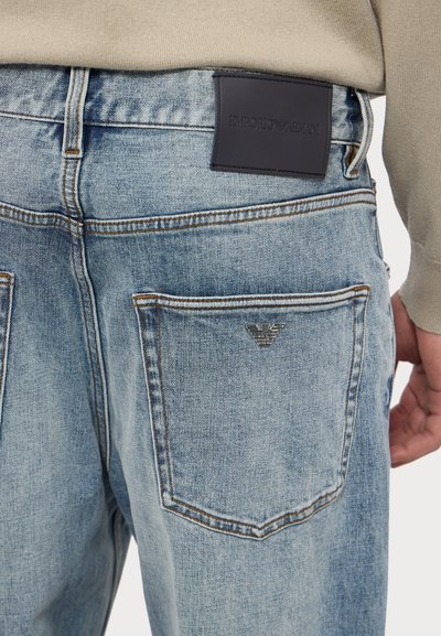 Ανοιχτό μπλε τζιν παντελόνι με δερμάτινη ετικέτα Emporio Armani στη μέση και ένα μικρό λογότυπο στην πίσω τσέπη. Παραδοσιακό σχέδιο πέντε τσεπών.