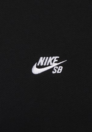 Tecido preto com uma textura suave, apresentando um logotipo bordado da Nike SB em branco, em uma fonte clássica. Design simples e moderno.