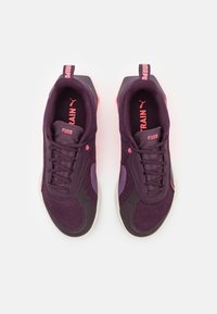 Lila Sportschuhe mit pinken Akzenten, ausgestattet mit einem gestrickten Obermaterial, texturierten Seitenpaneelen und einer weißen Sohle. Das Branding ist auf der Zunge sichtbar.