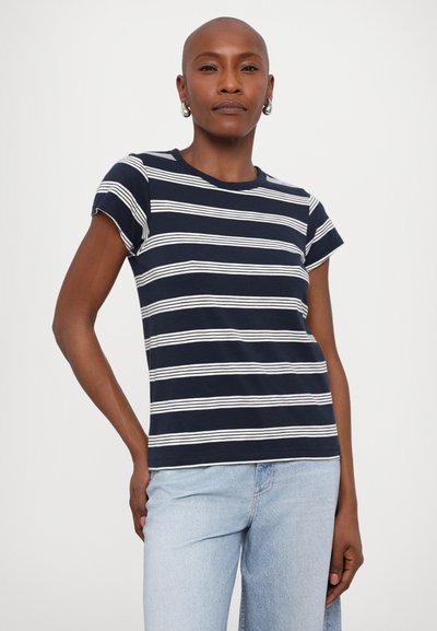 Marineblå stribet t-shirt med hvide vandrette striber, korte ærmer, rund halsudskæring, lavet af blødt stof, parret med lyseblå jeans.