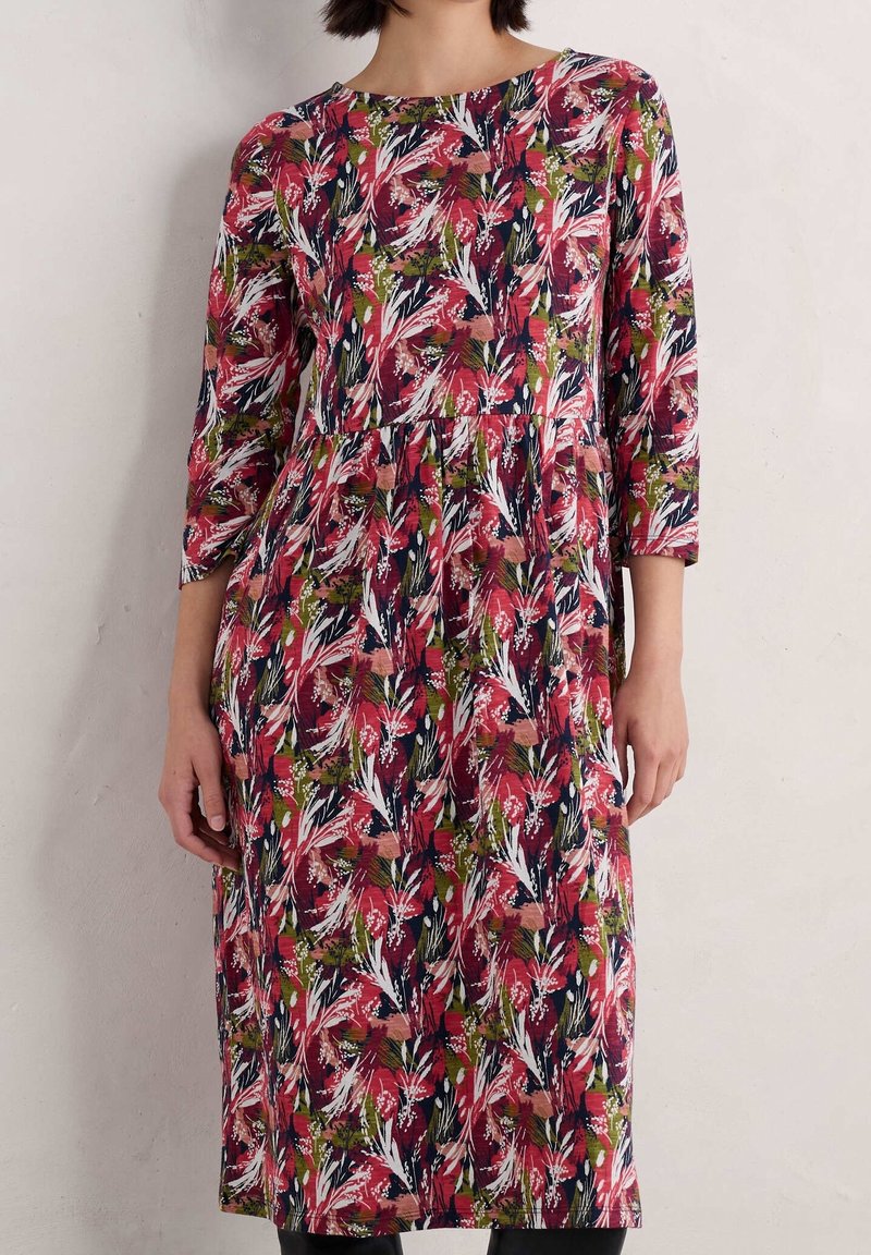 Sukienka w kwiatowy print w odcieniach czerwieni, różu i zieleni na ciemnym tle. Posiada rękawy o długości trzech ćwiartek oraz marszczoną talię.