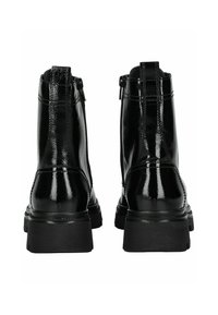 Botas de tobillo de charol negro con un acabado brillante, que presentan una cremallera corta, suela gruesa y detalles de costura a lo largo de los lados.