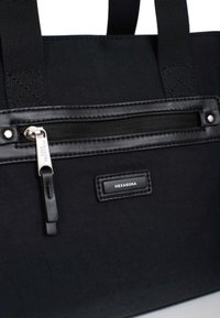 Borsa a spalla in tessuto nero con tasca con zip, dettagli in pelle e un'etichetta con logo. Manico rinforzato per una maggiore durata.
