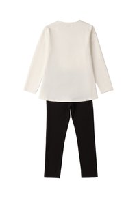 Maglietta bianca a maniche lunghe abbinata a pantaloni neri slim-fit, mostrata piatta, vista da dietro su uno sfondo bianco.