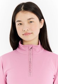 Svetloružový top s dlhým rukávom a vysokým golierom, s polovičným zipsom a detailom loga. Hladká textúra so jemnými vyšívacími akcentmi.