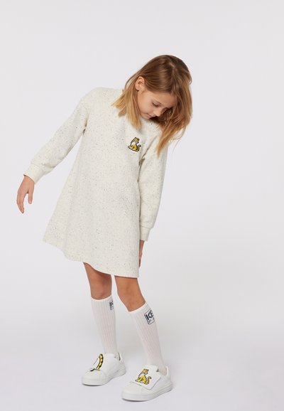 Robe-sweat beige clair avec une texture mouchetée, décolleté rond et manches longues. Présente une broderie de tigre jaune sur la poitrine.