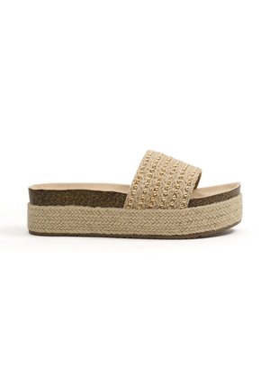Sandalia tipo slide beige con plataforma, suela trenzada, entresuela de corcho y adornos de cuentas doradas en la tira ancha de tela.