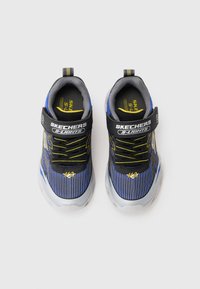 Baskets Skechers S-Lights présentant un design bleu et gris, un motif rayé, une sangle noire, des accents jaunes et une semelle rembourrée.