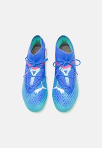 Blue athletic shoes featuring a knitted upper, gradient sole, patterned mesh, and reflective accents with blue laces.