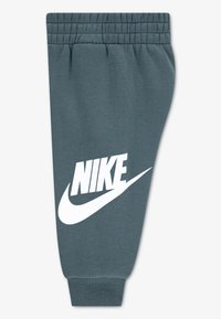 Γκρι φόρμα με ελαστική μέση, διαθέτει μεγάλο λευκό λογότυπο Nike και σχέδιο swoosh στο αριστερό πόδι. Μαλακό βαμβακερό υλικό.