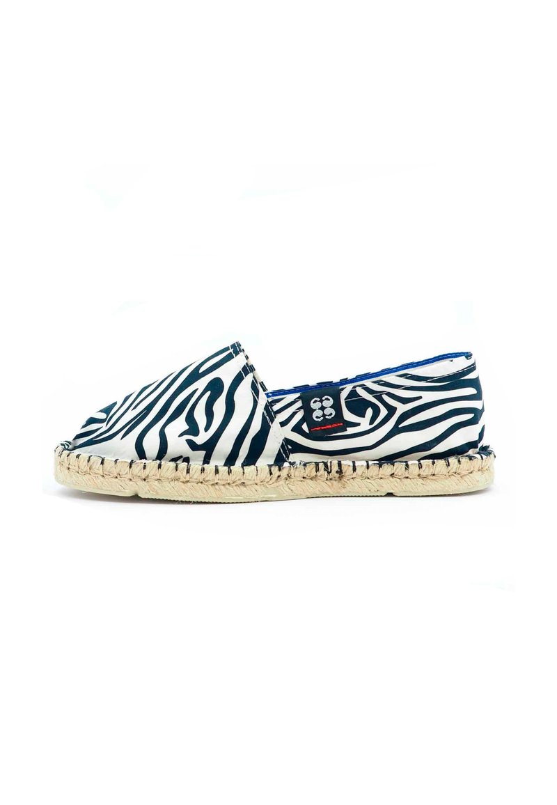Espadrille à imprimé zèbre avec un dessus en toile noir et blanc, présentant une semelle en jute tissée et une doublure intérieure bleue.