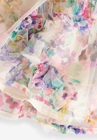 Tissu transparent avec imprimé floral coloré et délicats volants superposés dans des tons pastel de rose, violet, vert et jaune.