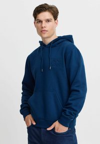 Navy blue hoodie made of soft cotton blend, features a kangaroo pocket, drawstring hood, and embossed "ENJOY" logo on the chest.