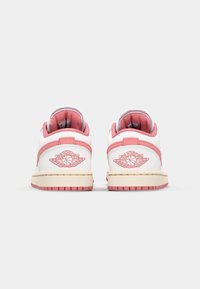 Baskets basses blanches et roses au toucher doux, avec un logo sur le talon, des coutures contrastantes et une semelle en caoutchouc.