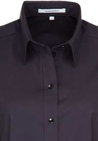Chemise noire à boutons, fabriquée dans un tissu doux. Présente un col classique et six boutons noirs sur le devant. L'étiquette indique "seidensticker."